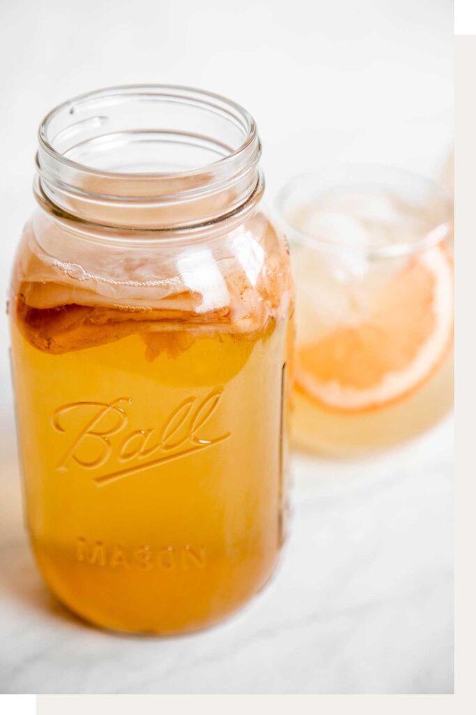 a mason jar with a growing SCOBY floating on the surface of the kombucha